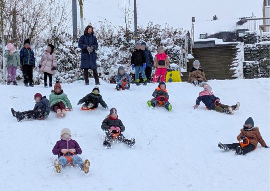 Kinder und Erwachsene haben Spaß beim Schlittenfahren im Schnee.
